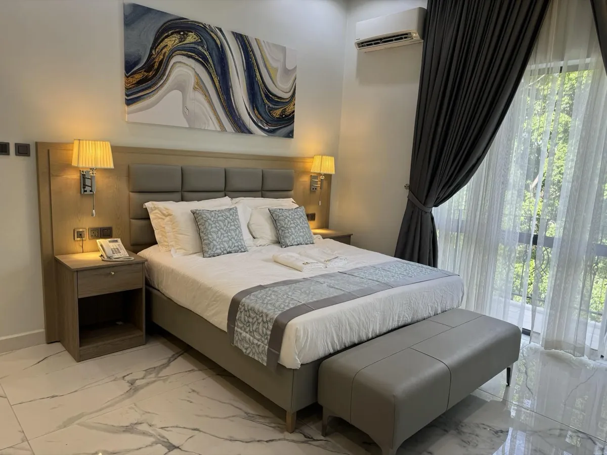 A finished bedroom with a custom upholstered headboard, fitted side tables and wall panelling