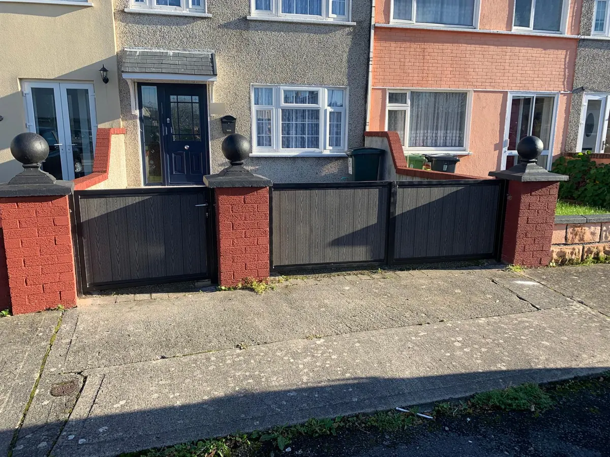 Low steel framed driveway gates and a matching pedestrian gate with grey composite infill between red brick piers