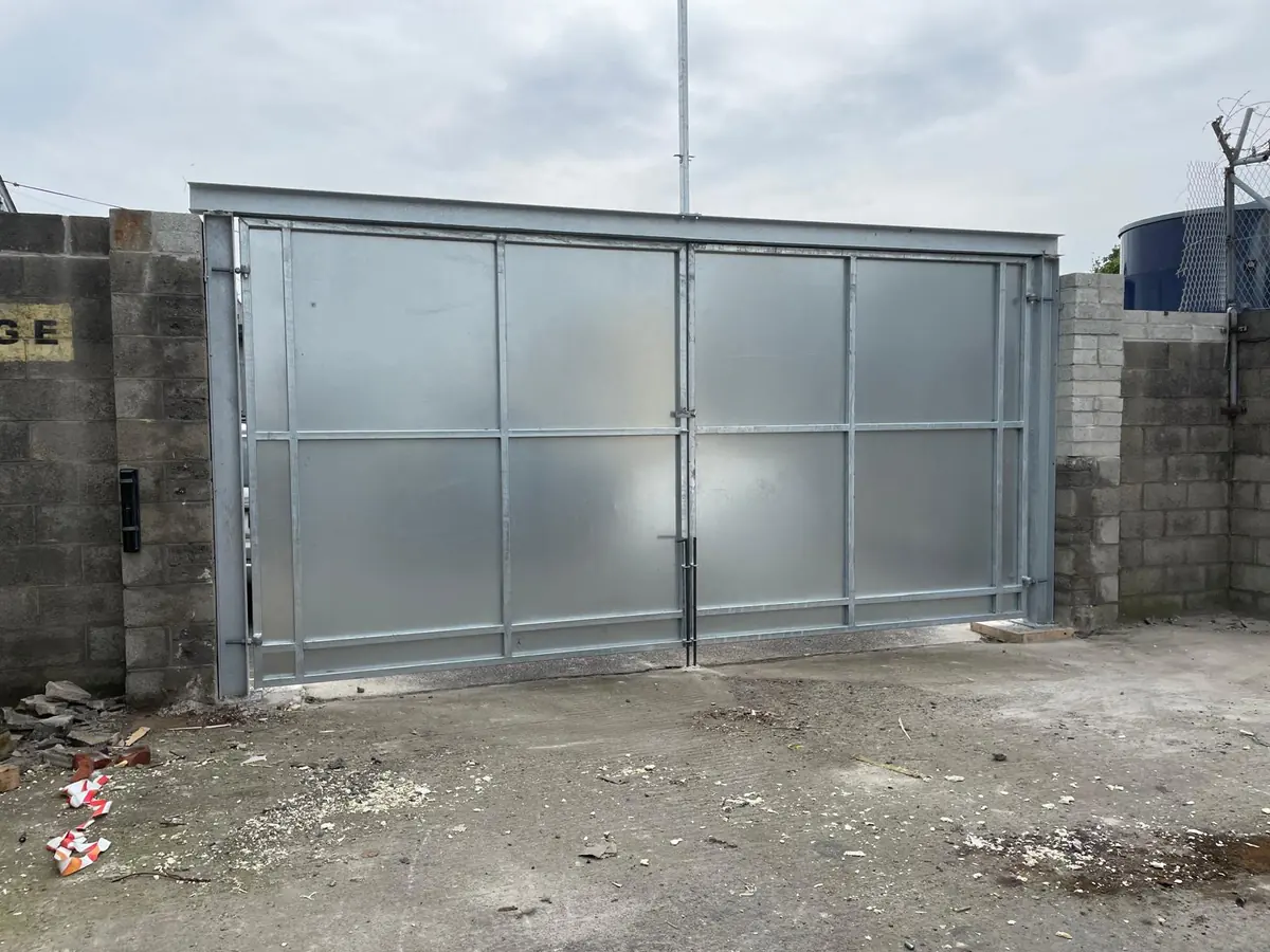 A pair of galvanised sheeted steel yard gates under a steel lintel beam, made and fitted for a commercial premises