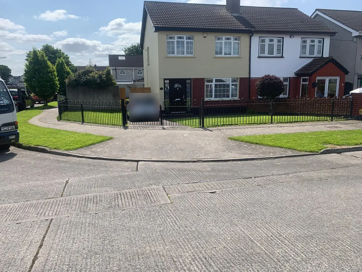 Low black hoop top metal railings and gates running along the front garden of a semi detached house