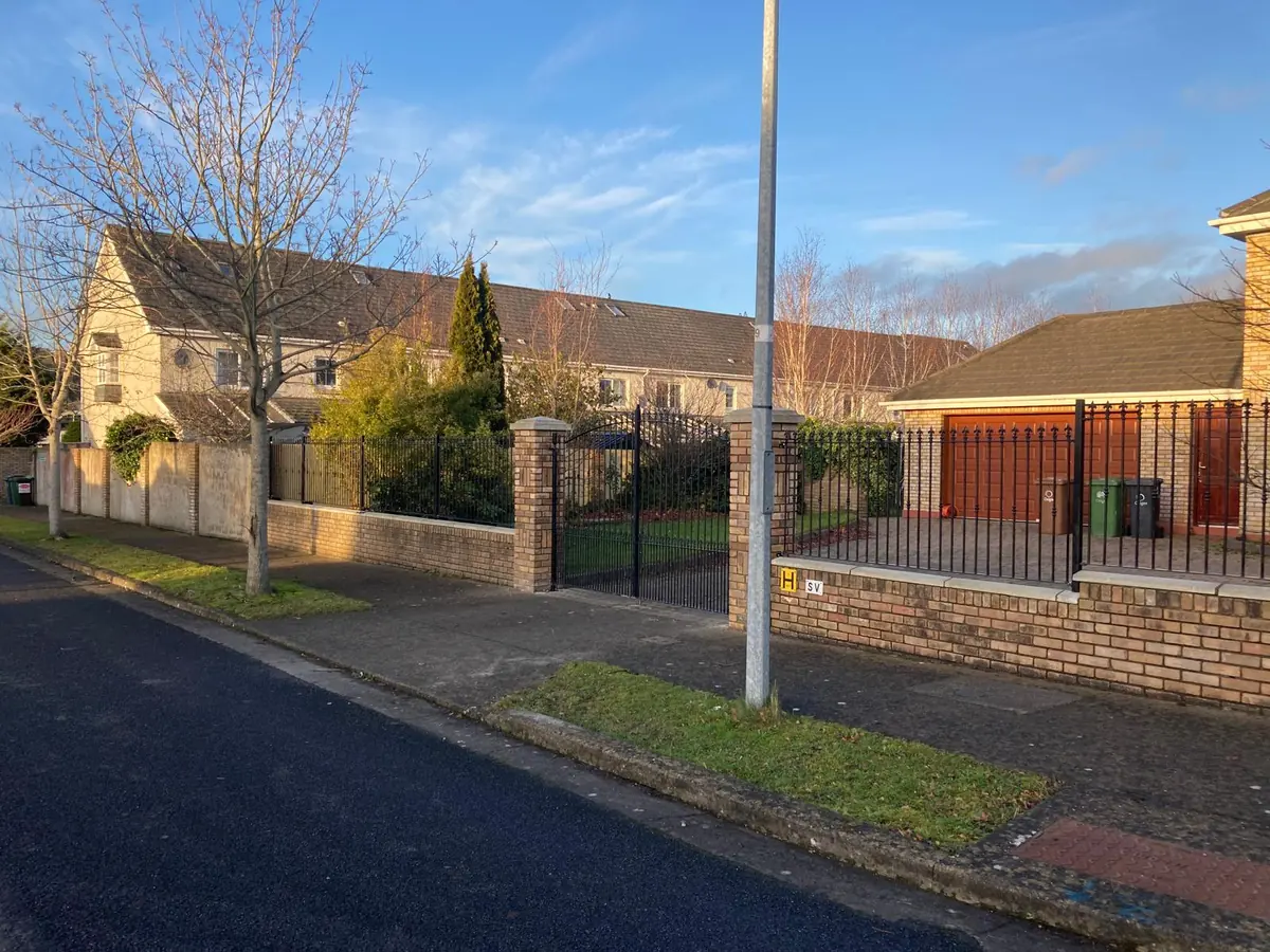 Wrought iron style railings and a matching pedestrian gate between brick piers