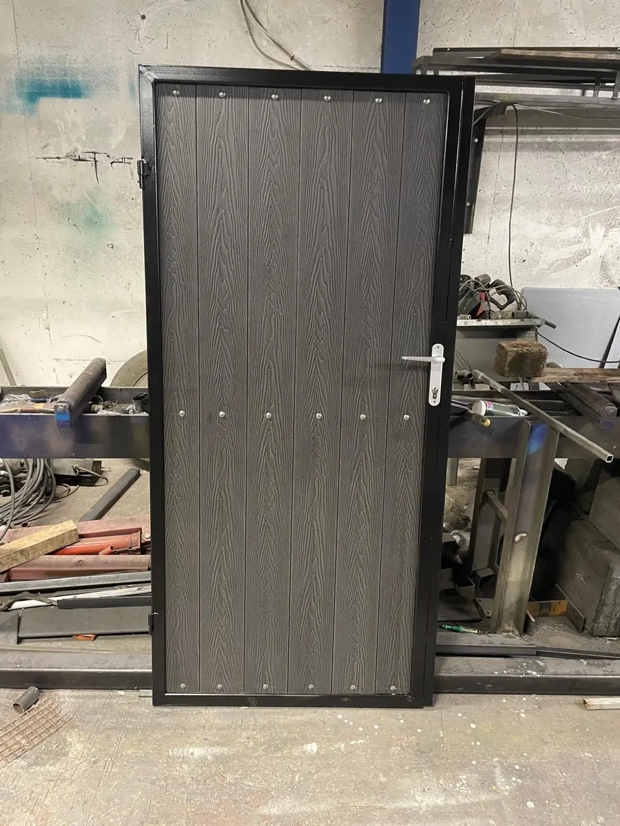 A made to order steel framed side gate with composite board infill standing in the gate maker's workshop before fitting