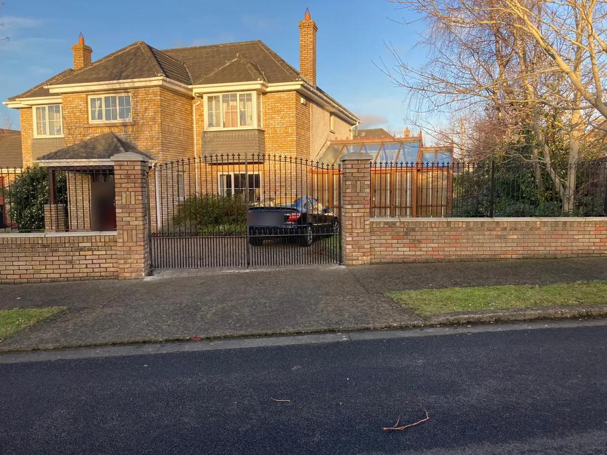 Wrought iron style double driveway gates with matching railings along a brick front wall