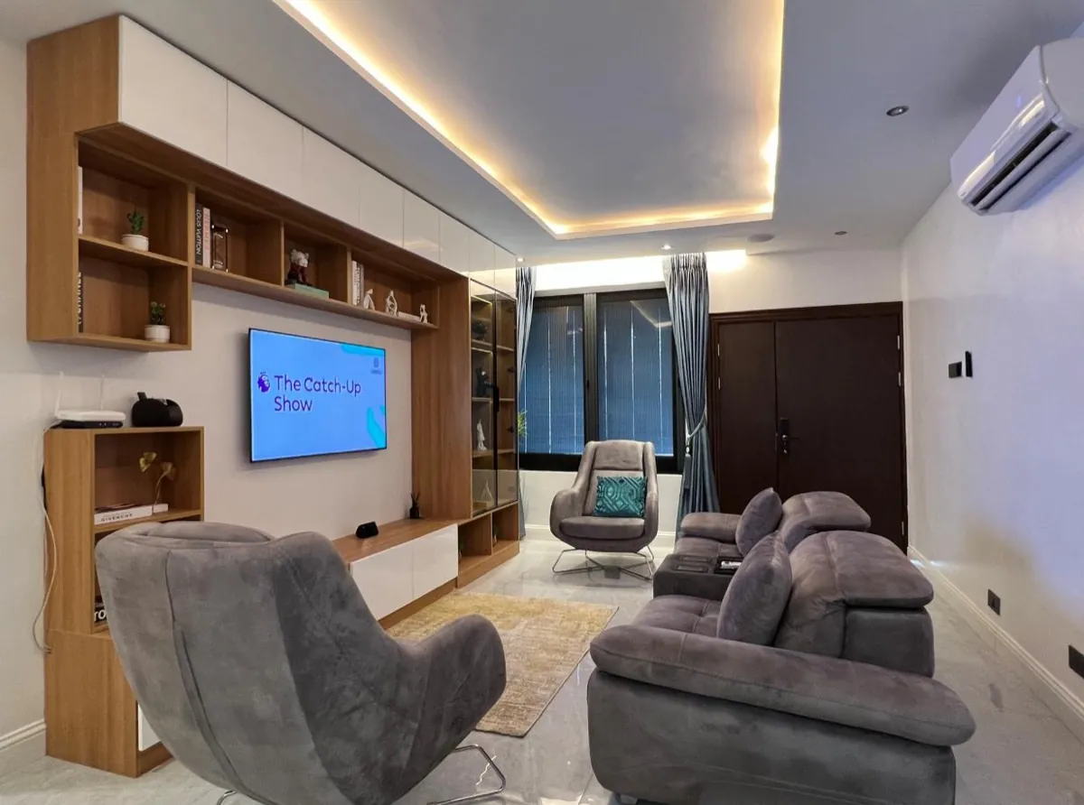 A living room with a custom fitted media wall, shelving and display cabinet
