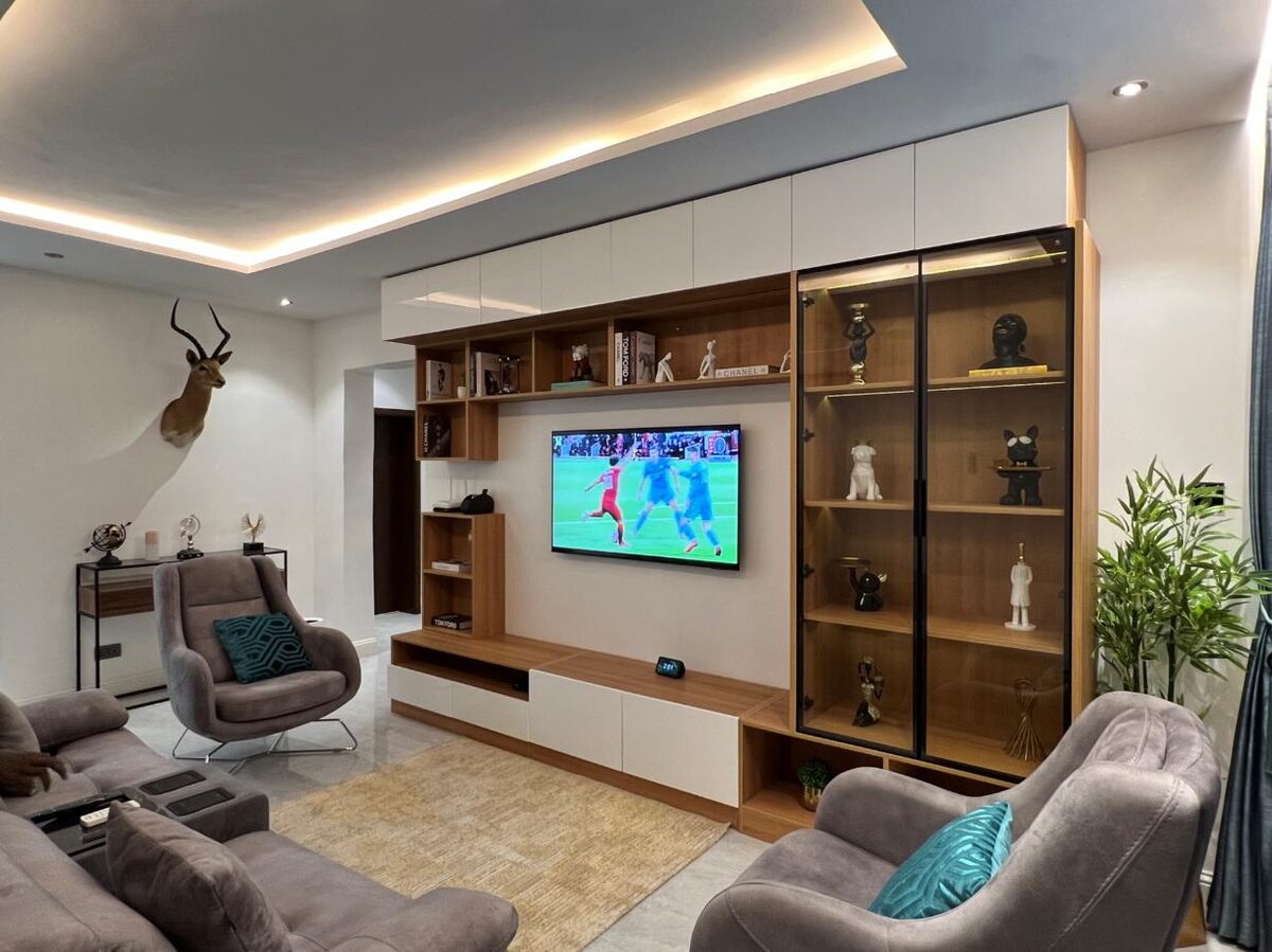 A living room with a fitted media wall, display cabinets and shelving