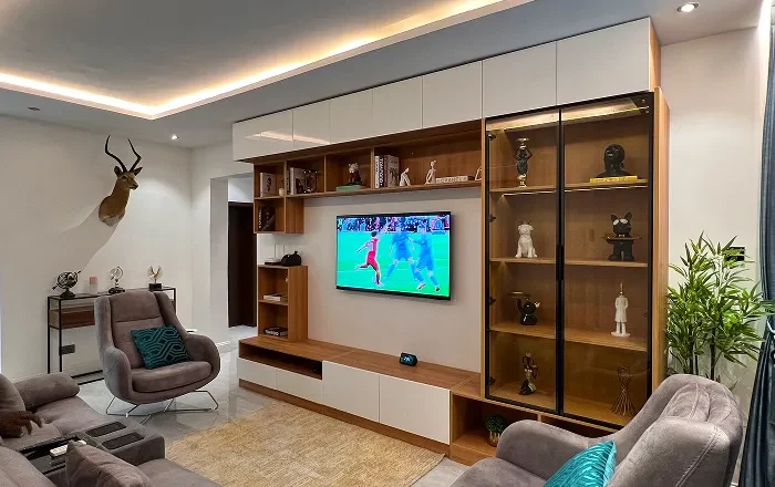 A fitted media wall with a wall mounted television, timber cabinetry and lit glass display units