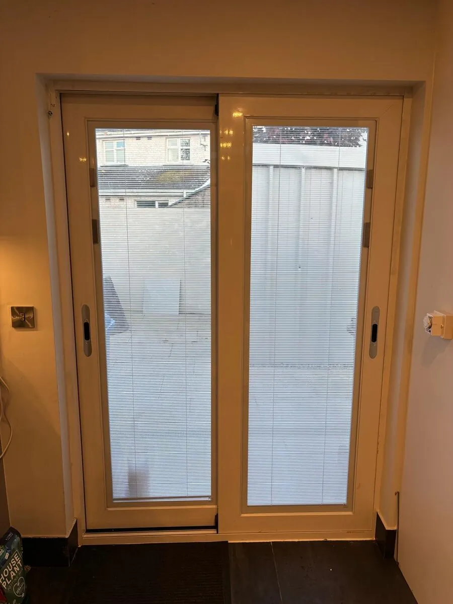 A white sliding patio door seen from inside a Dublin home, closed, with blinds